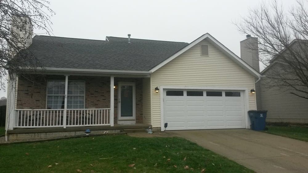 Single-story suburban home with a brick facade, white siding, and a two-car garage.
