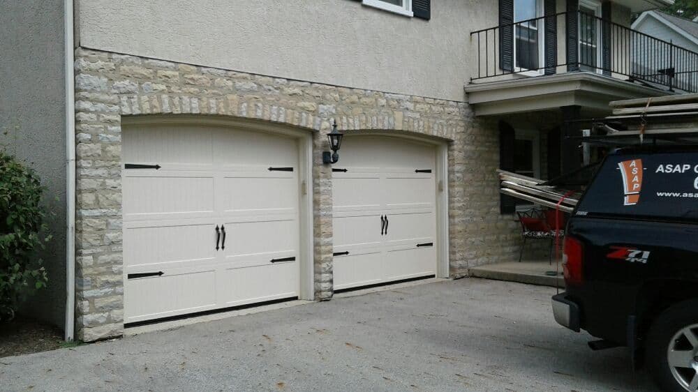 Elegant two-car garage with stone accents and black hardware, set in a residential area.