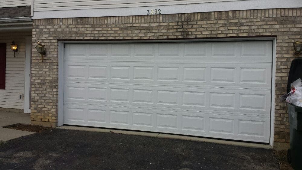 White garage door in a brick wall, featuring a horizontal panel design.