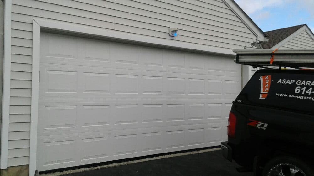 White garage door on a home with an ASAP Garage truck parked nearby.