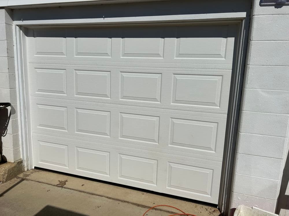White garage door with paneled design, installed on a residential building.