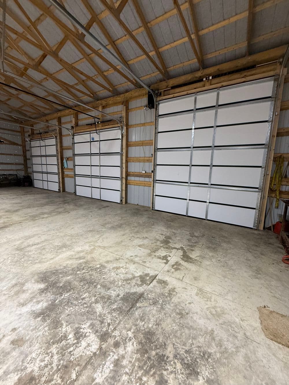 Spacious garage interior with three large white garage doors and concrete flooring.